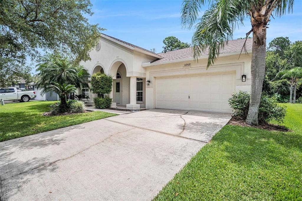 A single-story house with a beige stucco exterior, arched entryway, and a two-car garage — 16909 FALCONRIDGE ROAD, LITHIA, FL