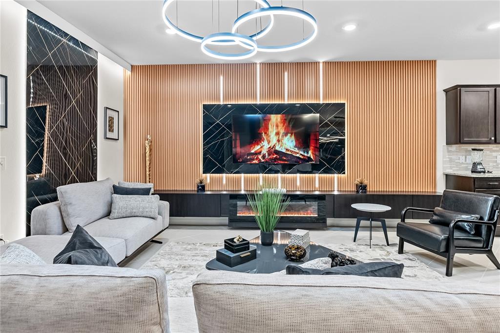 A modern living room features a slatted wood wall with a black marble fireplace and TV — 15969 CAPE CORAL LOOP, CLERMONT, FL