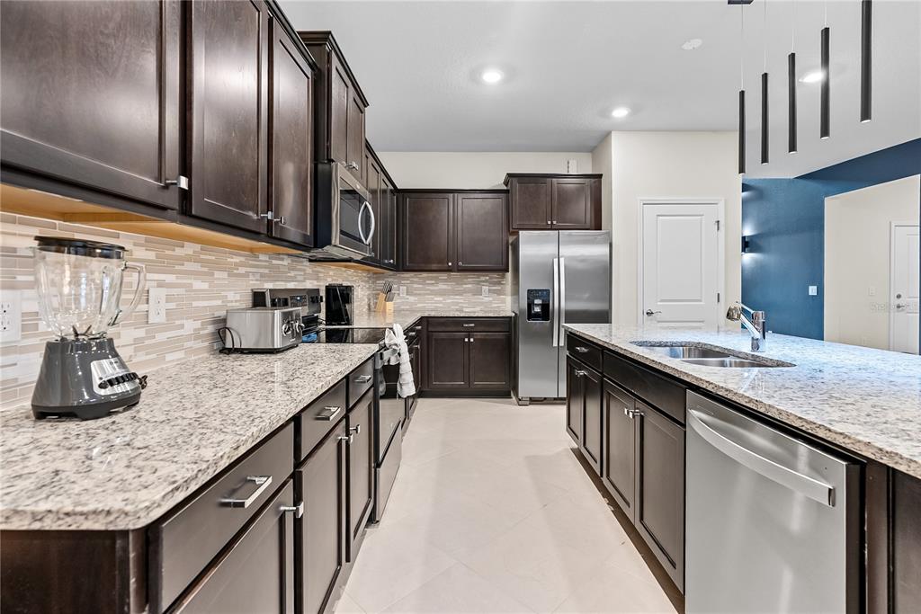 A kitchen features dark wood cabinets, granite countertops, stainless steel appliances, and a central island — 15969 CAPE CORAL LOOP, CLERMONT, FL