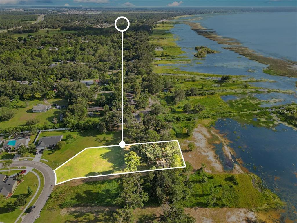An aerial view shows a vacant, rectangular lot bordering a large lake and trees — 4810 CALASANS AVENUE, ST CLOUD, FL