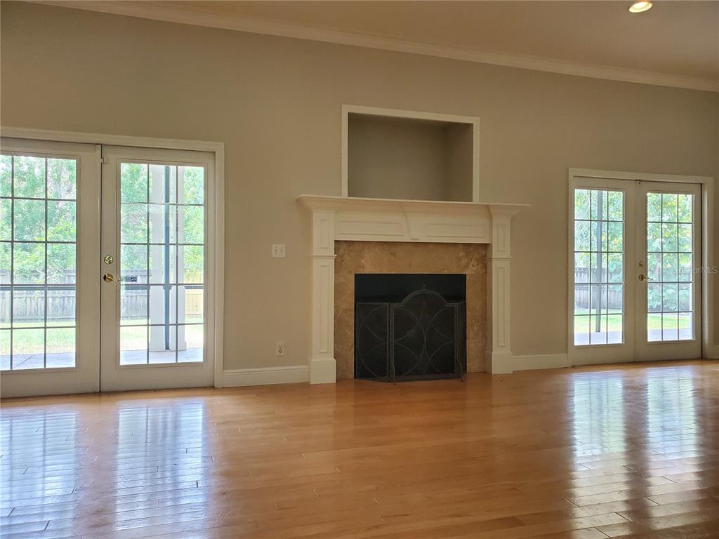 An interior view shows a staircase with wooden railings next to a room with hardwood floors — 2121 FAIRFIELD AVENUE, BRANDON, FL