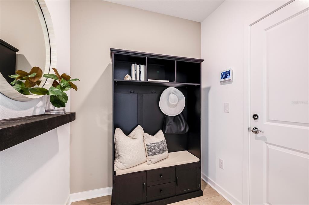 A mudroom entry features a black storage bench, a wall-mounted mirror, and a white door — 16817 HARMONY RIVER LANE, PARRISH, FL