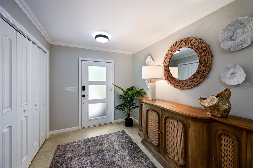 An entryway features a wood console table, a round mirror, a rug, and a front door — 430 BIRD KEY DRIVE, SARASOTA, FL