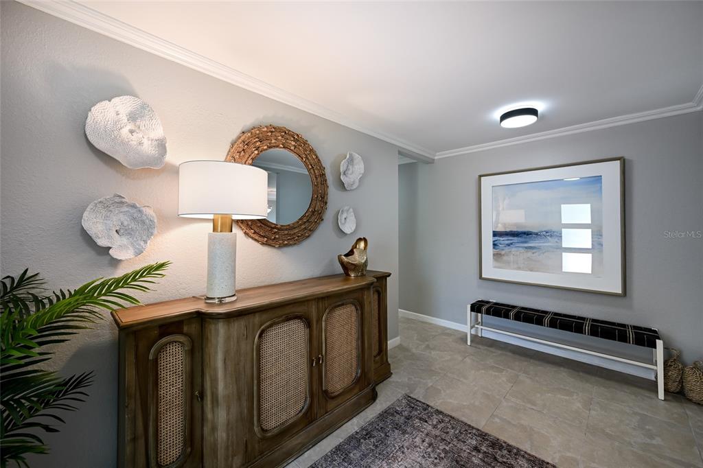 A foyer features a wooden sideboard, a round mirror, wall art, and a bench — 430 BIRD KEY DRIVE, SARASOTA, FL