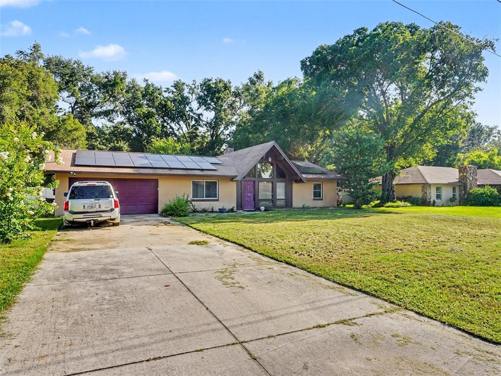 A single-story house with a purple garage door, solar panels, and a concrete driveway — 128 N POINTE DRIVE, AUBURNDALE, FL