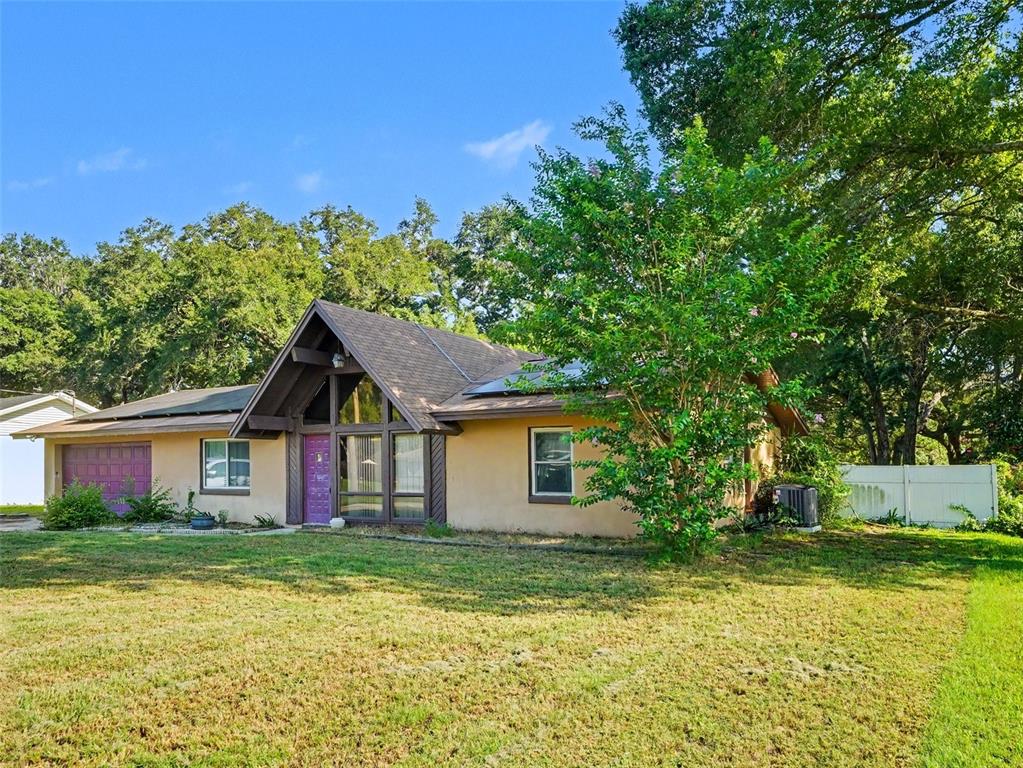 A tan, single-story house with a prominent A-frame entryway and a purple front door — 128 N POINTE DRIVE, AUBURNDALE, FL