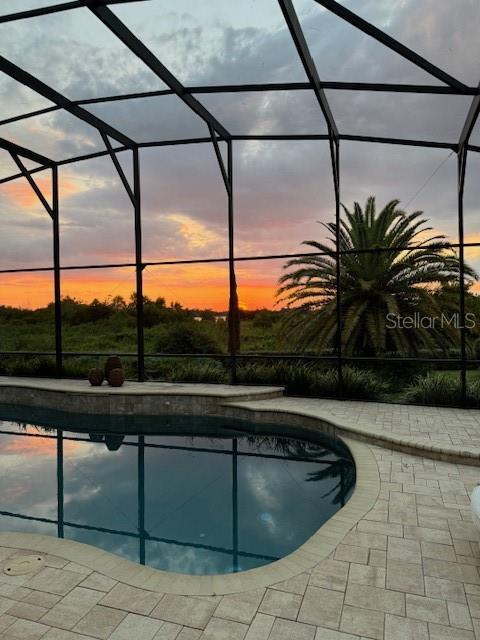 A swimming pool with a screen enclosure overlooks a sunset over a grassy landscape — 1641 EDGEWATER DRIVE, MOUNT DORA, FL