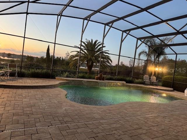 A screened-in patio features a swimming pool, stone pavers, and a sunset view — 1641 EDGEWATER DRIVE, MOUNT DORA, FL