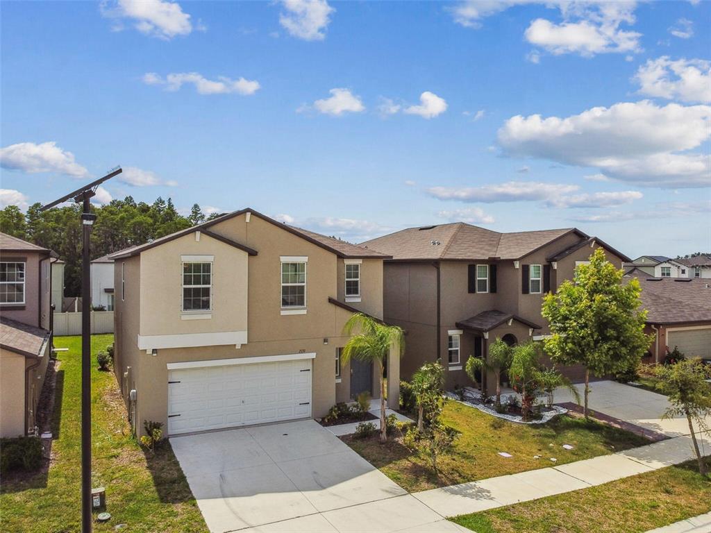 An exterior view of two adjacent two-story suburban houses with driveways and a blue sky — 2139 STELLAR BRILLIANCE WAY, LUTZ, FL