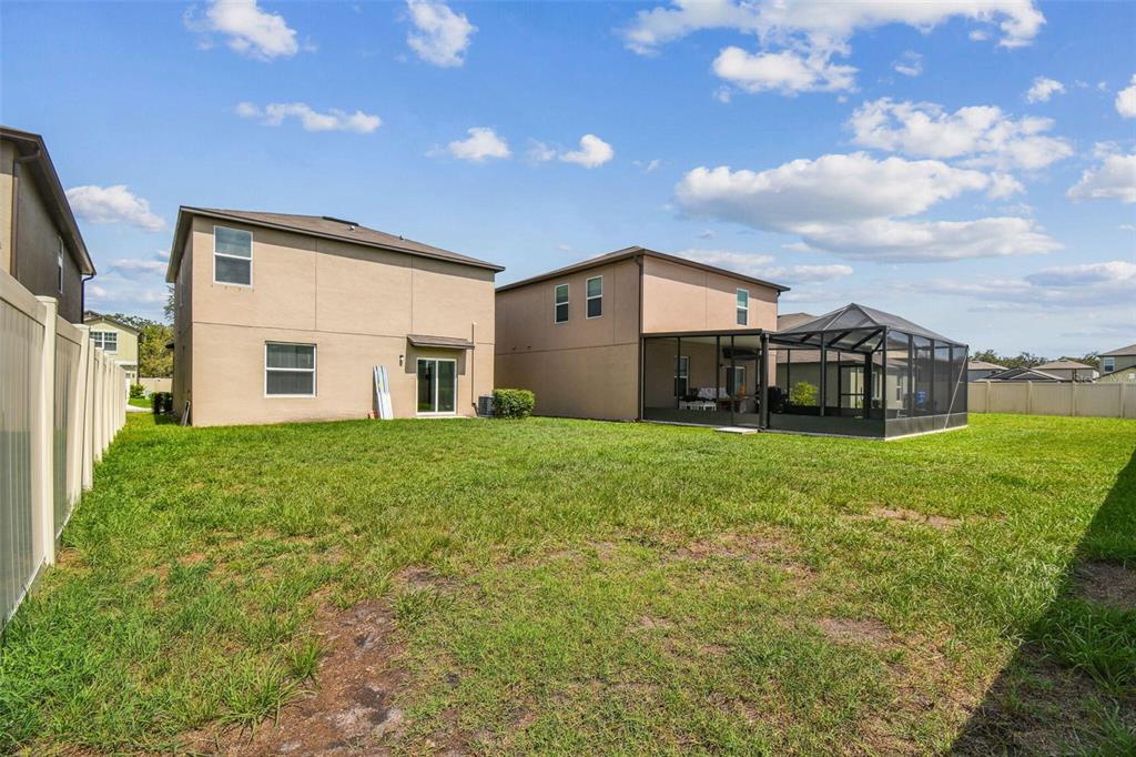The backyard features a grassy lawn between two two-story houses, one with a screened enclosure — 2139 STELLAR BRILLIANCE WAY, LUTZ, FL