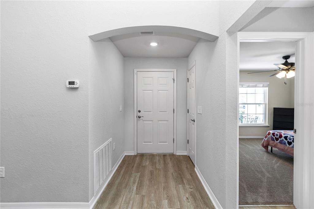 An entryway features light wood-look flooring, a white front door, and an arched ceiling — 8968 SE 46TH TERRACE, OCALA, FL