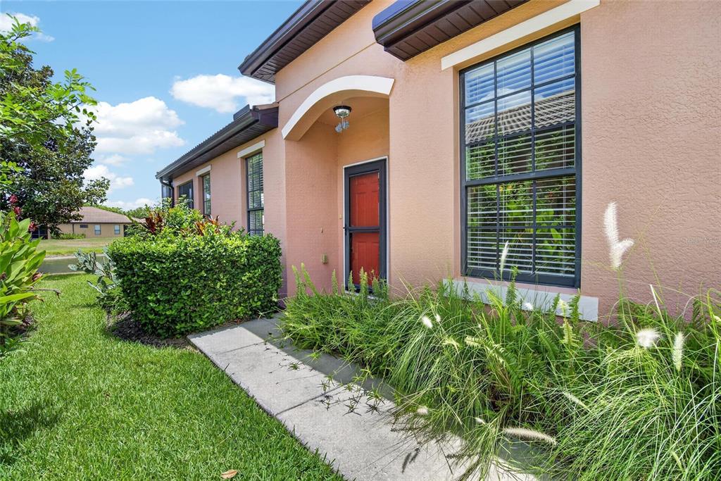 A peach-colored house exterior features a red front door, a concrete walkway, and landscaping — 132 SHELL FALLS DRIVE, APOLLO BEACH, FL
