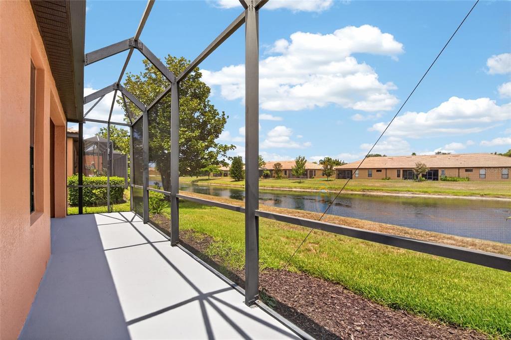 A screened-in patio overlooks a narrow canal and neighboring houses under a blue sky — 132 SHELL FALLS DRIVE, APOLLO BEACH, FL