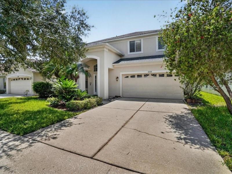 A two-story suburban house features a beige exterior, a two-car garage, and a concrete driveway — 10420 LUCAYA DRIVE, TAMPA, FL
