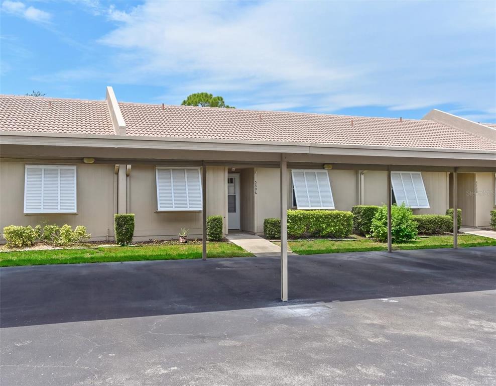 A single-story residential building features a covered carport, beige siding, and white window shutters — 5506 37TH STREET E UNIT 4, BRADENTON, FL