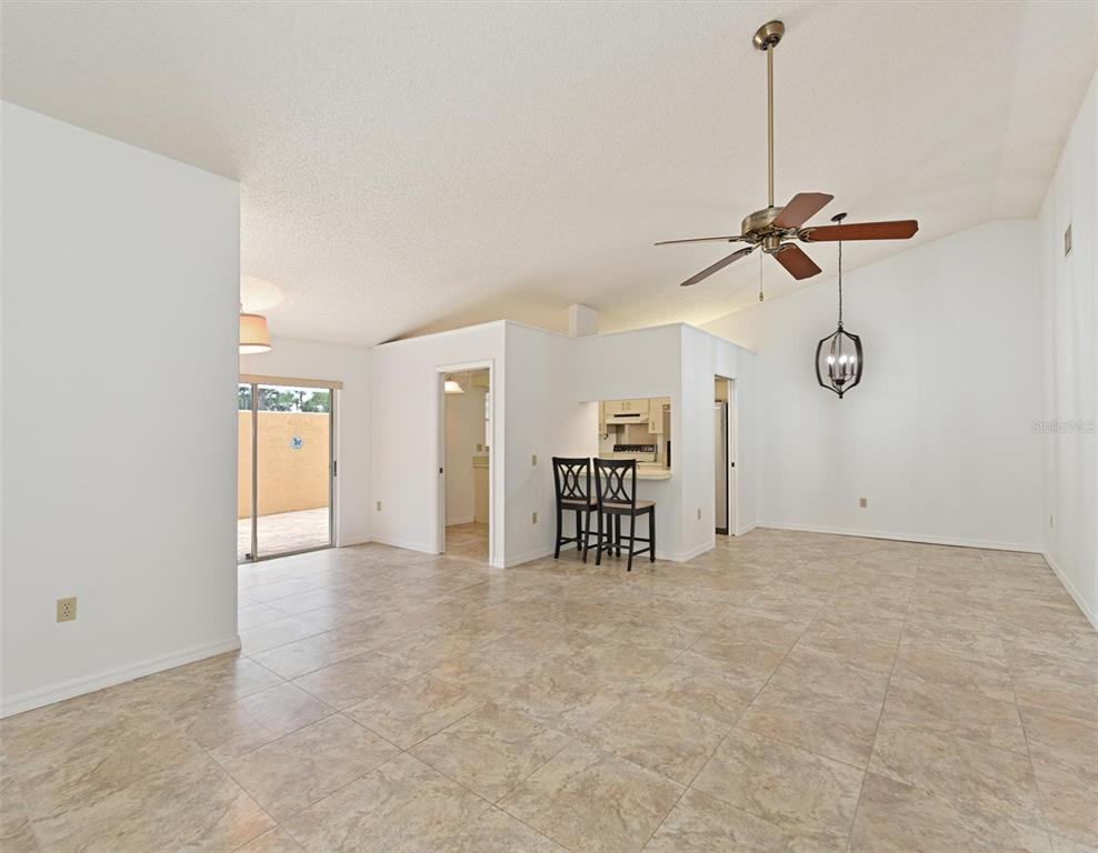 A spacious living area with tile flooring, a vaulted ceiling, and a kitchen pass-through window — 5506 37TH STREET E UNIT 4, BRADENTON, FL