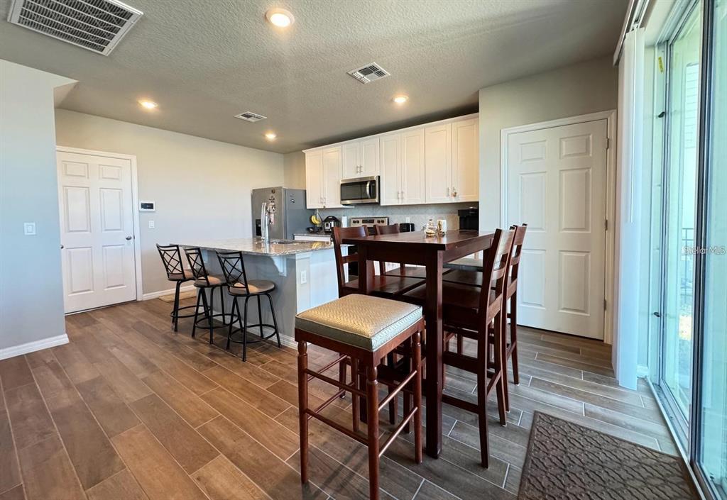 A kitchen with white cabinets, a granite island, and a wooden dining table — 520 WHISTLING DUCK TRAIL, ST CLOUD, FL