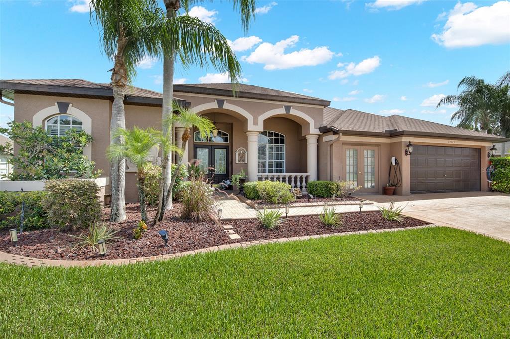 A single-story house with a brown roof, stucco exterior, arched entryway, and a two-car garage — 22523 WILLOW LAKES DRIVE, LUTZ, FL