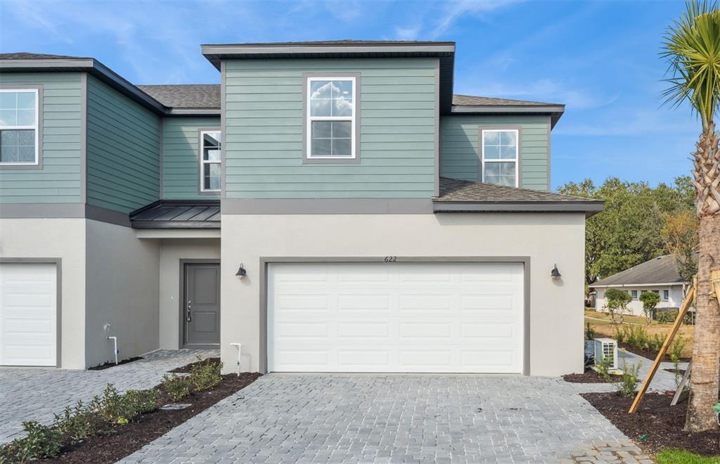 A two-story townhouse with a white garage door, gray front door, and teal siding — 2291 RED PINE COURT, EUSTIS, FL