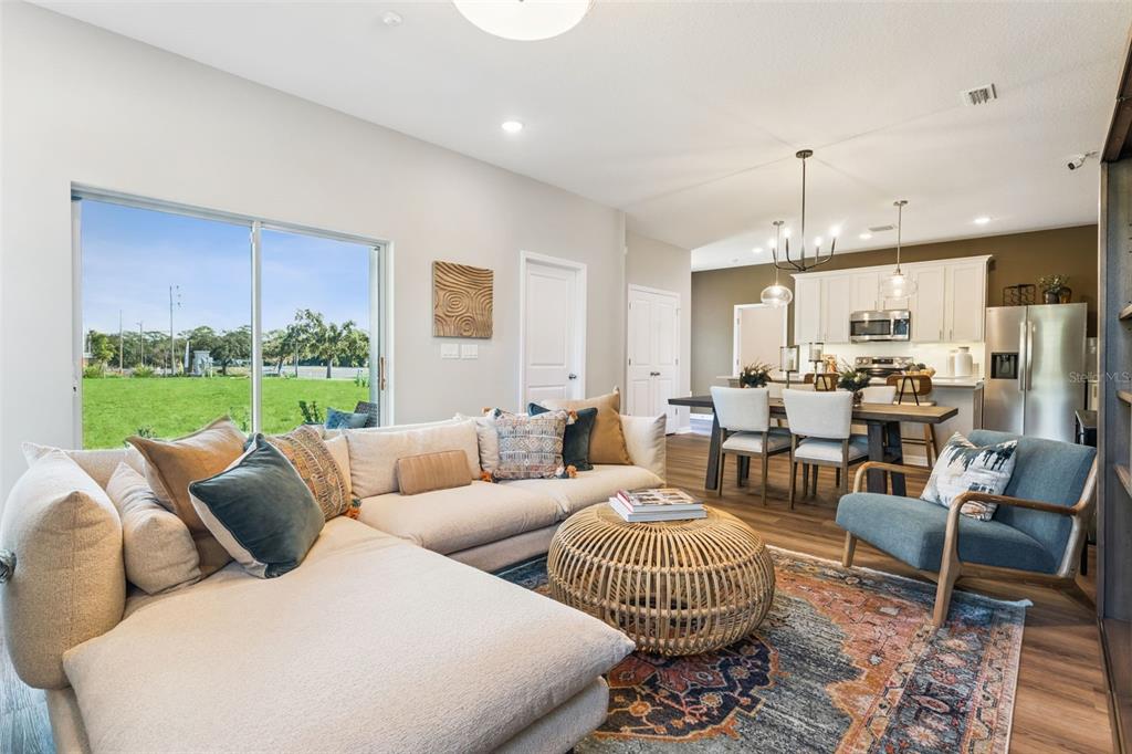 An open-concept living and dining area features a large sectional sofa, rug, and kitchen — 2291 RED PINE COURT, EUSTIS, FL