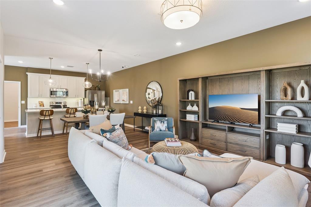 An open-concept living room and kitchen feature wood-look flooring, a large sectional, and built-in shelving — 2291 RED PINE COURT, EUSTIS, FL