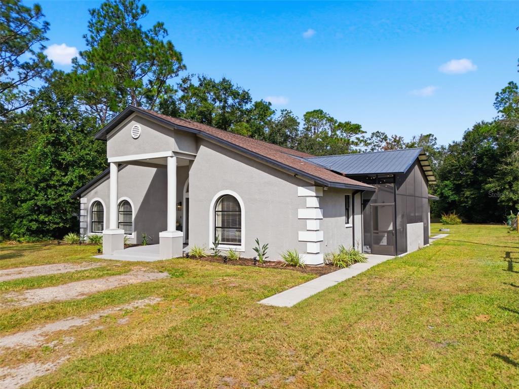 A gray house with a covered porch, arched windows, and a screened-in side patio — 28809 BENNINGTON DRIVE, WESLEY CHAPEL, FL