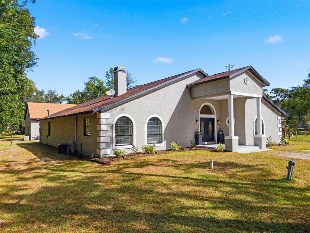 A single-story stucco house with a covered entryway, arched windows, and a detached garage — 28809 BENNINGTON DRIVE, WESLEY CHAPEL, FL