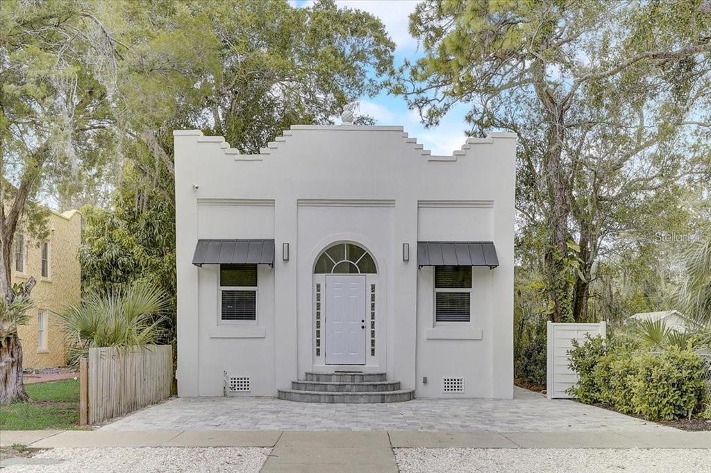 A white, single-story building with a stepped parapet roof, arched entryway, and two metal awnings — 1862 6TH STREET, SARASOTA, FL