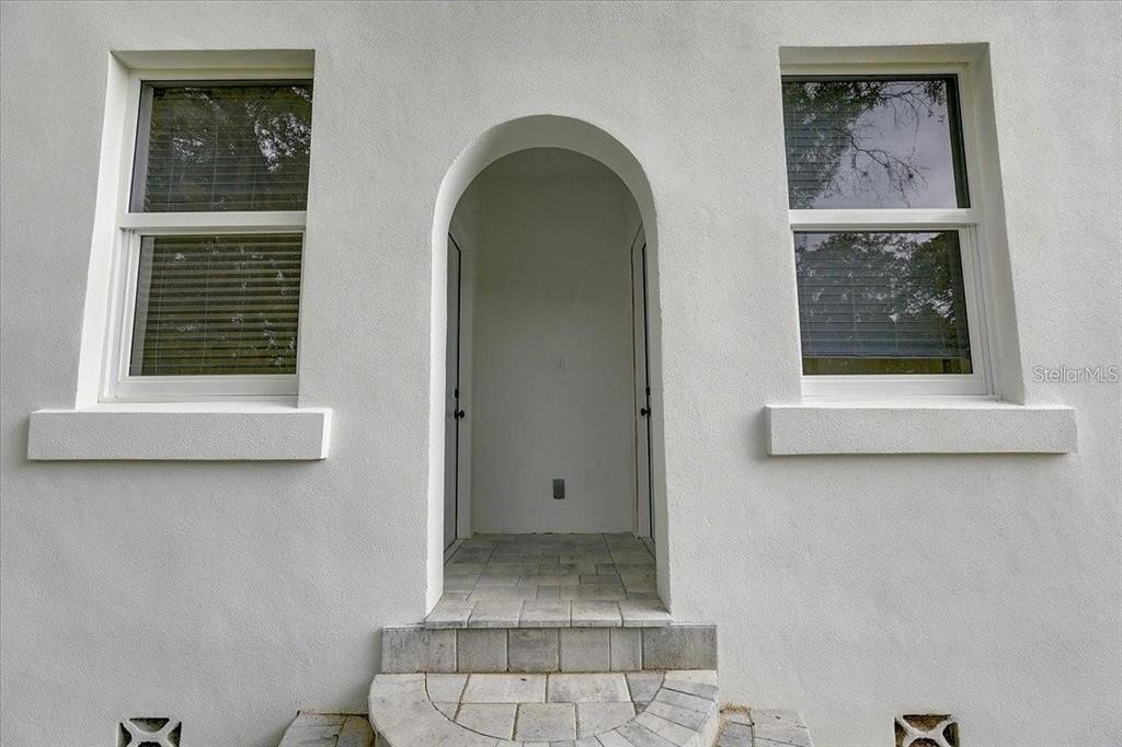 A white stucco exterior features two windows flanking an arched entryway with tiled steps — 1862 6TH STREET, SARASOTA, FL