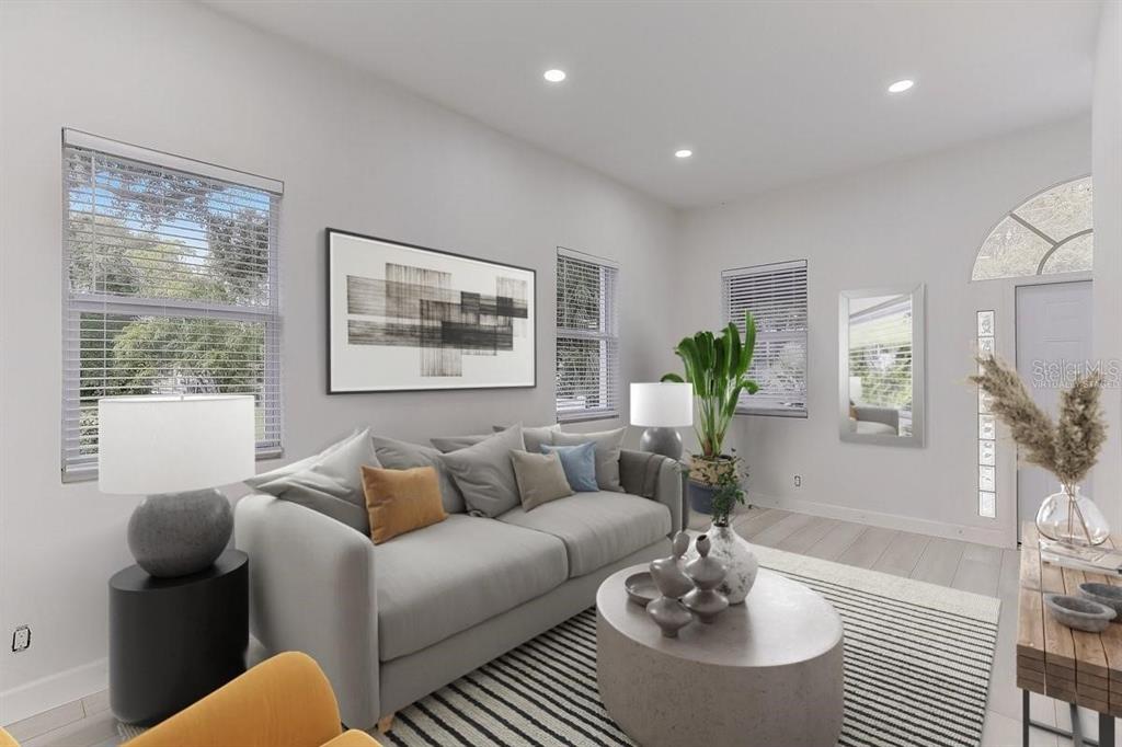 A bright living room features a gray sofa, a round coffee table, and large windows — 1862 6TH STREET, SARASOTA, FL