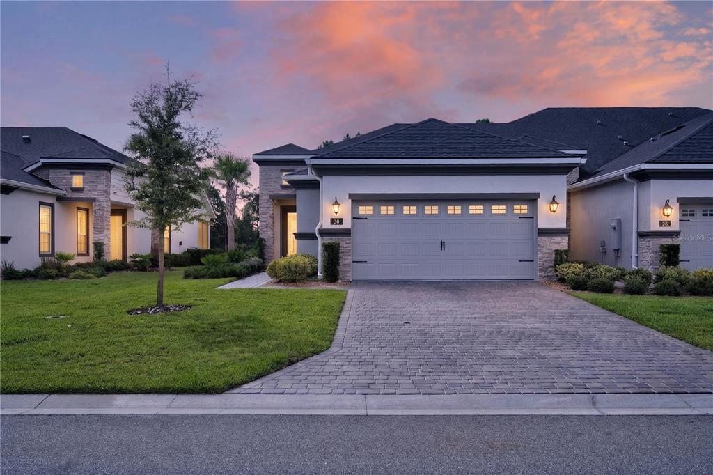 A suburban house exterior features a gray garage door, stone accents, and a paved driveway — 30 LONGRIDGE LANE, ORMOND BEACH, FL