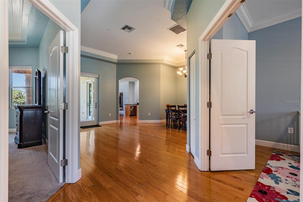 A hallway with hardwood floors leads to a dining area and a kitchen beyond — 2008 N POINTE ALEXIS DRIVE, TARPON SPRINGS, FL