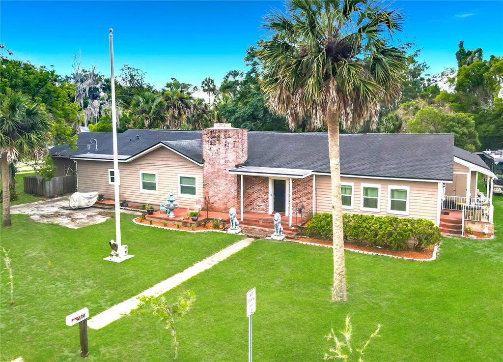 A single-story house with tan siding, a brick chimney, and a large front lawn — 474 E UNIVERSITY AVENUE, ORANGE CITY, FL