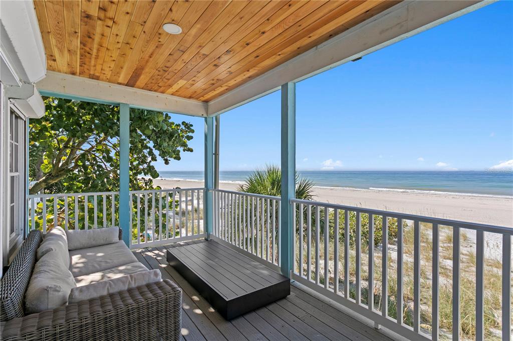 A two-story blue house with two garage doors and a balcony sits on a paved driveway — 20060 GULF BOULEVARD, INDIAN SHORES, FL