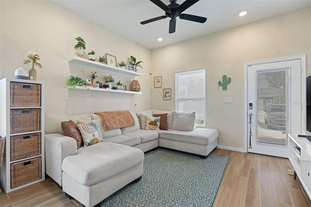A living room features a light-colored sectional sofa, floating shelves, and a patterned area rug — 3403 E 10TH AVENUE, TAMPA, FL