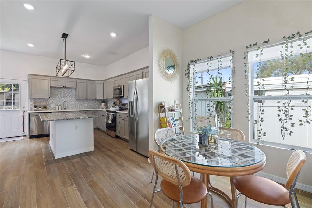 A kitchen with gray cabinets, a central island, and a dining area with a glass table — 3403 E 10TH AVENUE, TAMPA, FL