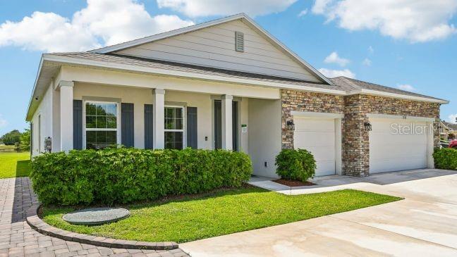 A single-story house with a stone facade, a two-car garage, and a manicured front hedge — TBD RAINBOW ROAD, VENICE, FL