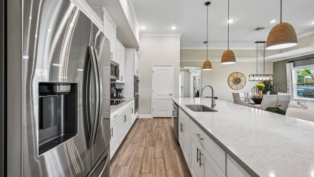 A modern kitchen features a stainless steel refrigerator, white cabinetry, and a large quartz island — TBD RAINBOW ROAD, VENICE, FL