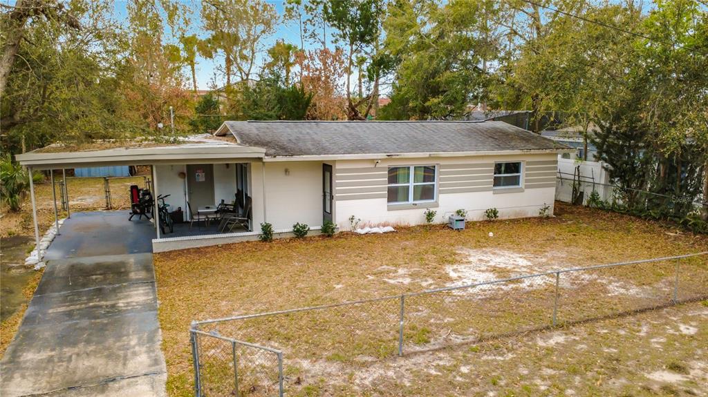 A single-story house with a carport, tan siding, and a chain-link fence in the yard — 741 HILLVIEW DRIVE, ALTAMONTE SPRINGS, FL
