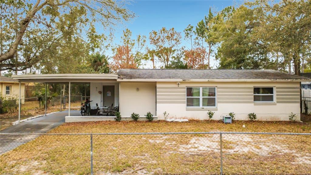 A single-story house with a carport, light-colored siding, and a chain-link fence in the yard — 741 HILLVIEW DRIVE, ALTAMONTE SPRINGS, FL