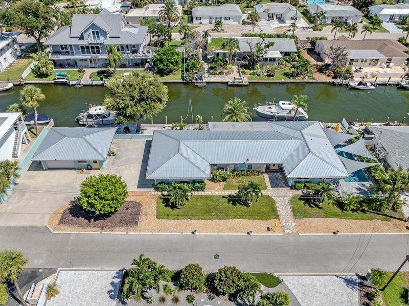 An aerial view shows a waterfront house with a metal roof, detached garage, and boat dock — 918 GIBBS ROAD, VENICE, FL