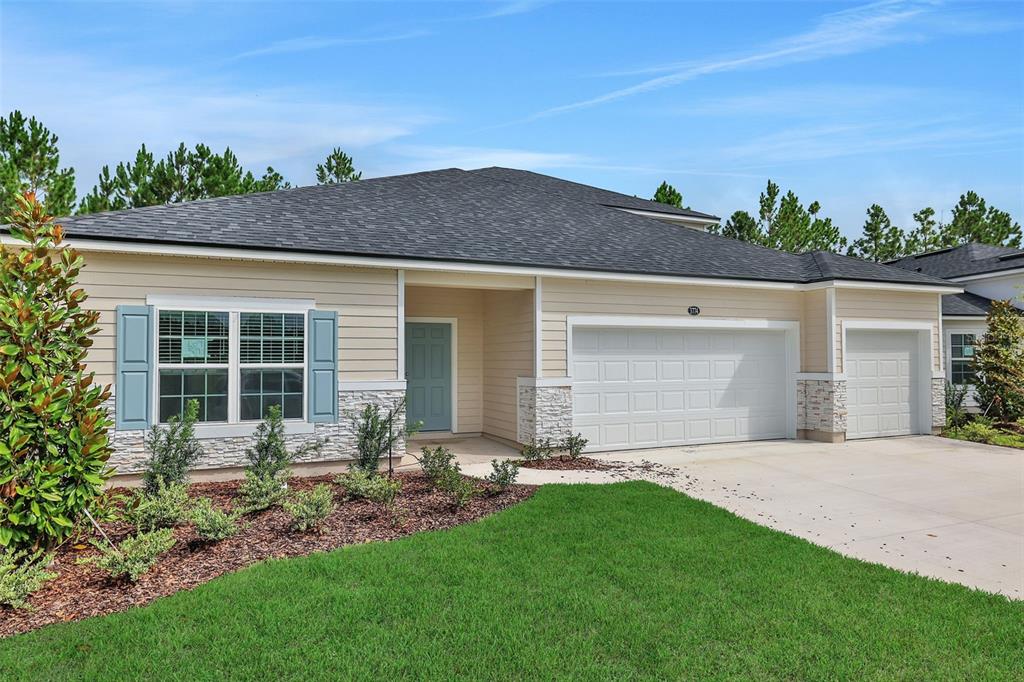 A single-story house with beige siding, a stone facade, and a three-car garage — 3702 HOLSTEIN WAY, GREEN COVE SPRINGS, FL