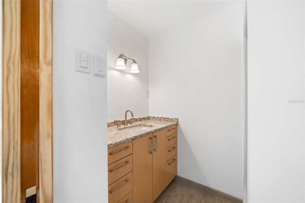 A small wet bar area features light wood cabinets, a granite countertop, and a sink — 177 E COWPEN LAKE ROAD, HAWTHORNE, FL