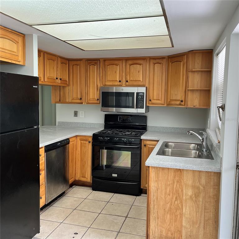 A kitchen features yellow walls, wooden cabinets, a double sink, and sliding glass patio doors — 207 BIRCH TERRACE, WINTER SPRINGS, FL