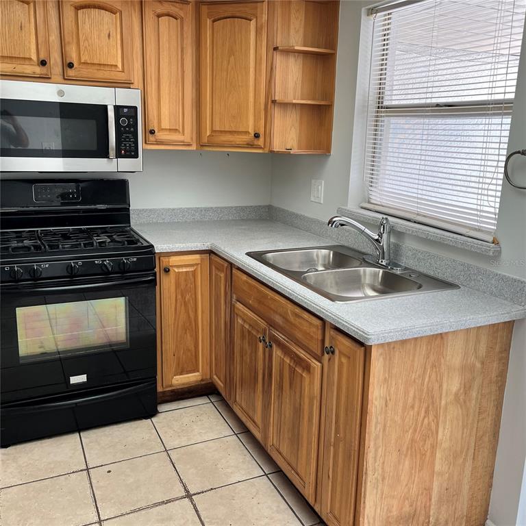 A kitchen with yellow walls, wood cabinets, a gas stove, and a sliding glass door — 207 BIRCH TERRACE, WINTER SPRINGS, FL