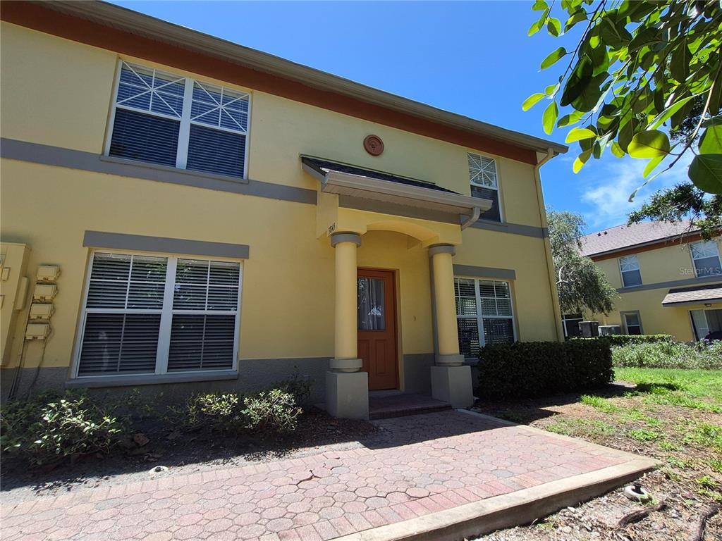 A yellow two-story building features a covered entrance with columns and a brick walkway — 3845 ISLAND WAY, ST PETERSBURG, FL