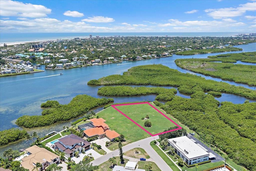 An aerial view shows a vacant rectangular lot outlined in pink near a coastal waterway — TIDEWOOD AVENUE, SARASOTA, FL