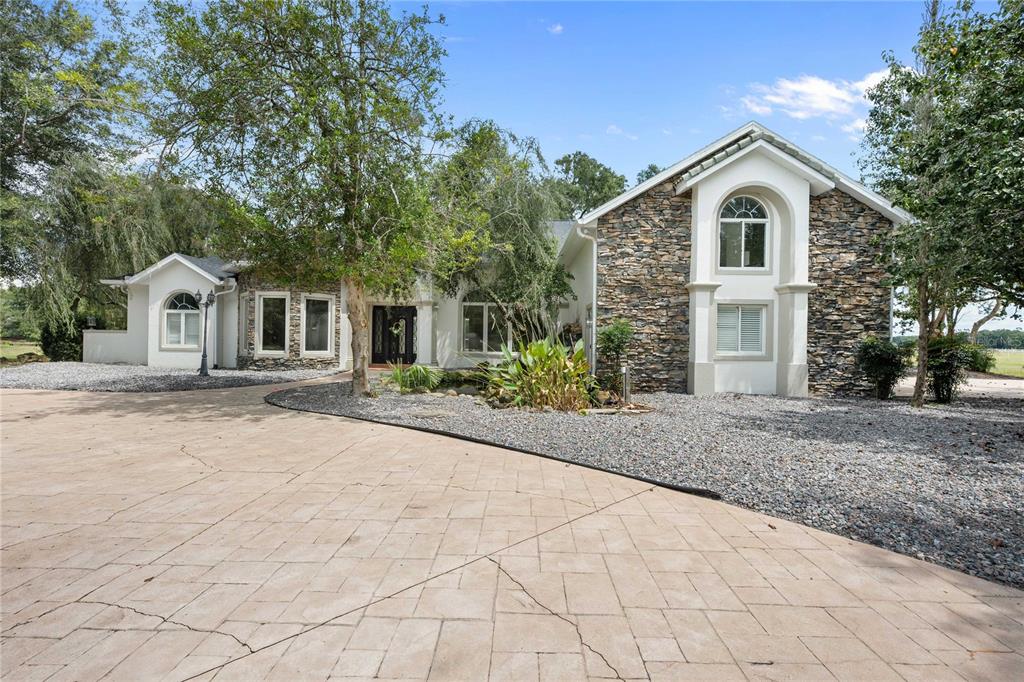 A single-story house with stone veneer siding and a large paved driveway — 17401 S HIGHWAY 475, SUMMERFIELD, FL