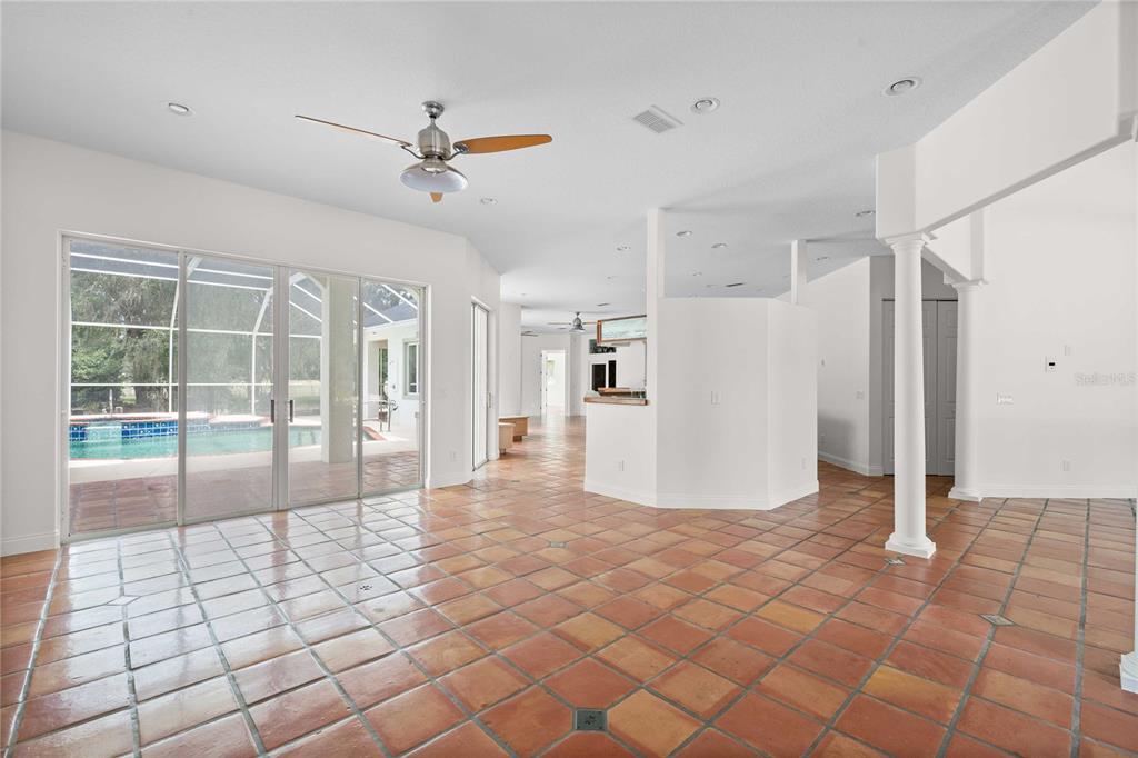 A spacious room with terracotta tile flooring, a ceiling fan, and sliding glass doors to a pool — 17401 S HIGHWAY 475, SUMMERFIELD, FL