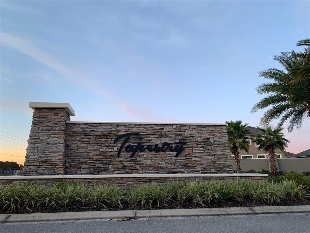 A stone monument sign with the word Tapestry stands in front of palm trees — 2860 CHANTILLY AVENUE, KISSIMMEE, FL